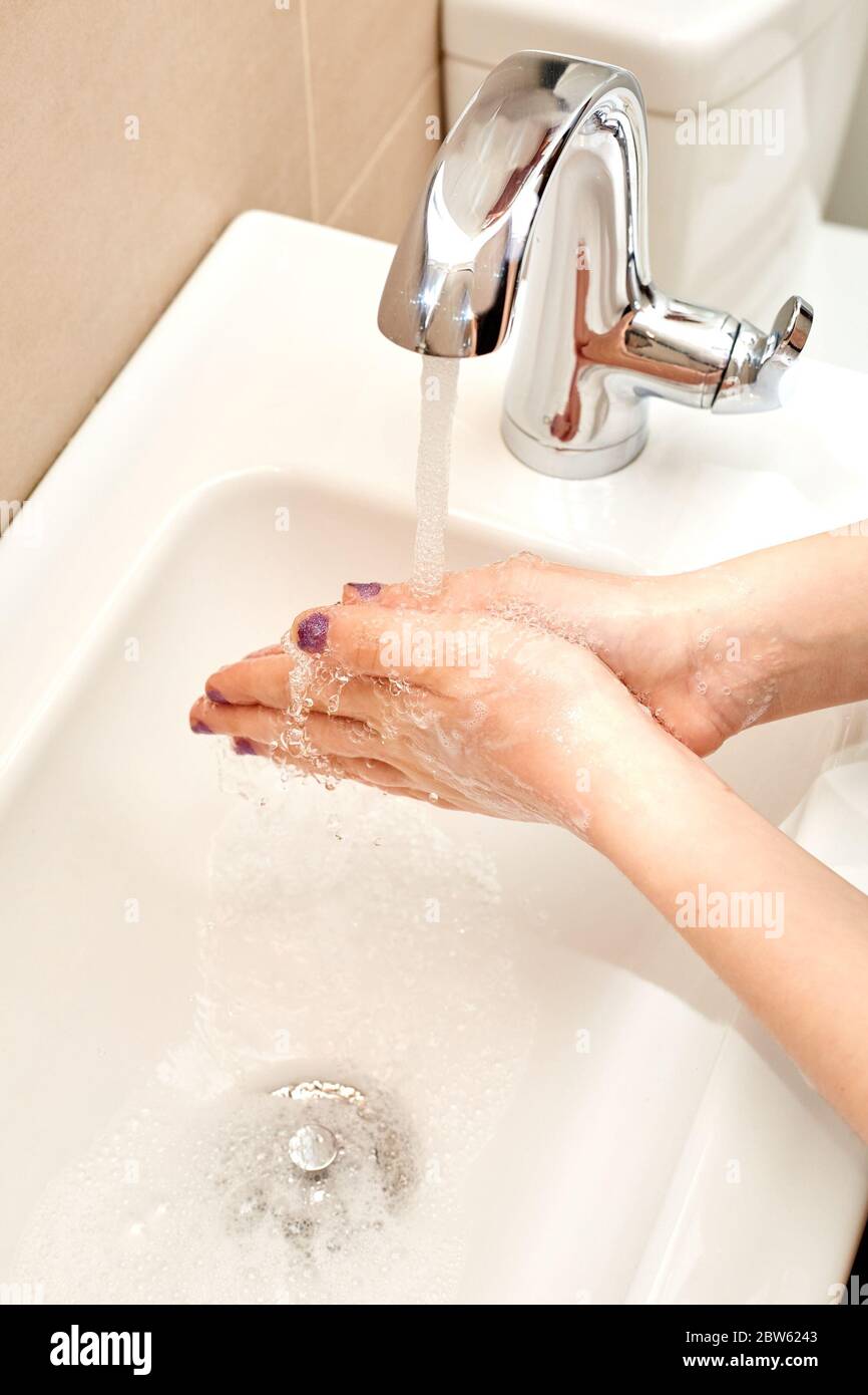 Blanc enfant se laver les mains avec du savon et de l'eau courante sur l'évier, les mains ensemble Banque D'Images