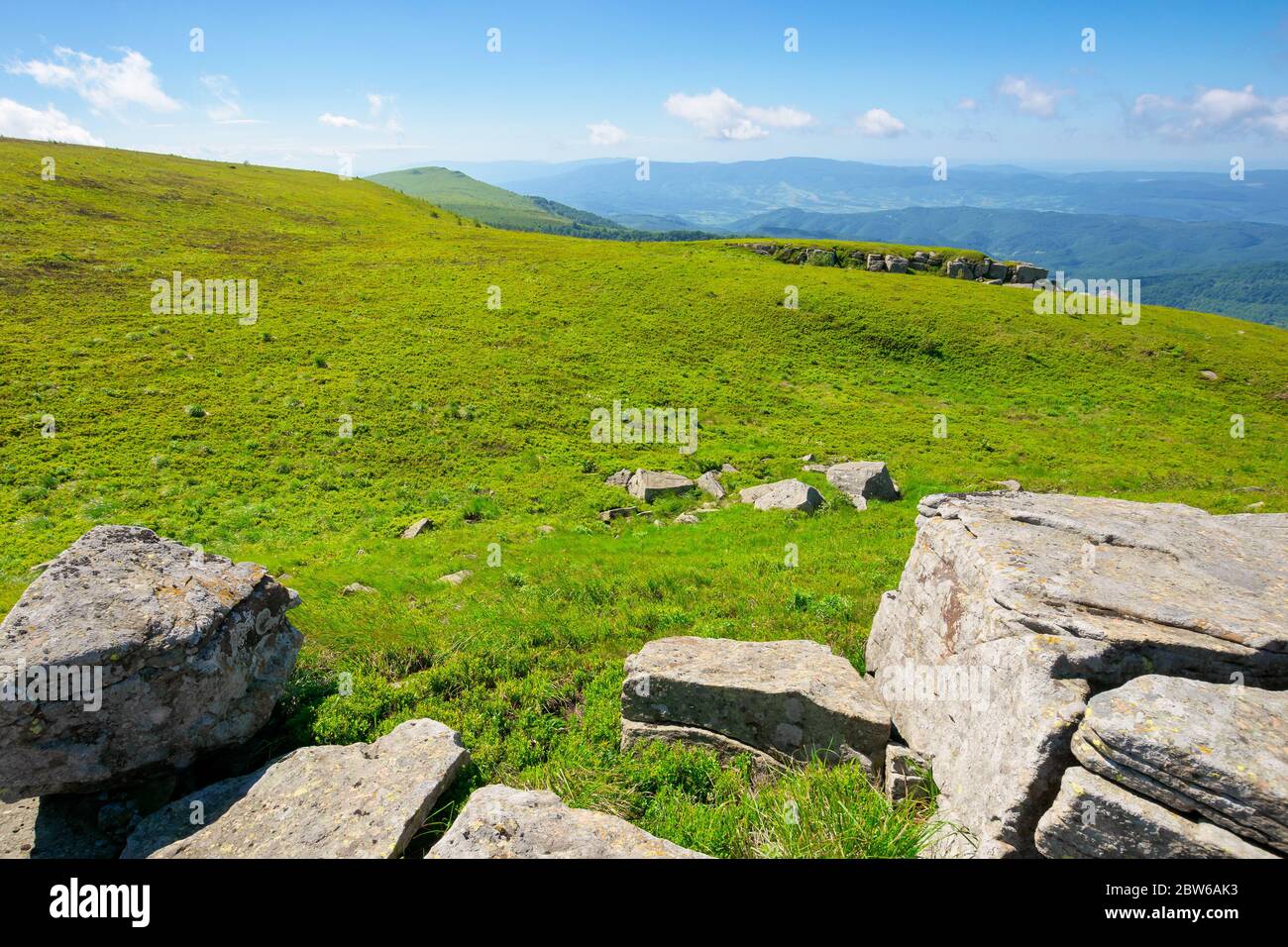 prairie de montagne en paysage d'été. ciel bleu avec des nuages moelleux. magnifique paysage d'été par une journée ensoleillée. rochers sur la pente au milieu de l'herbe. vue sur Banque D'Images