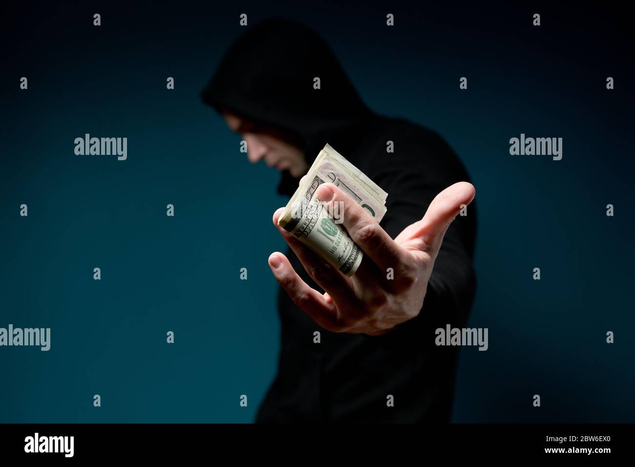 Un homme tient de l'argent et cache son visage. Silhouette sombre avec une seringue Banque D'Images