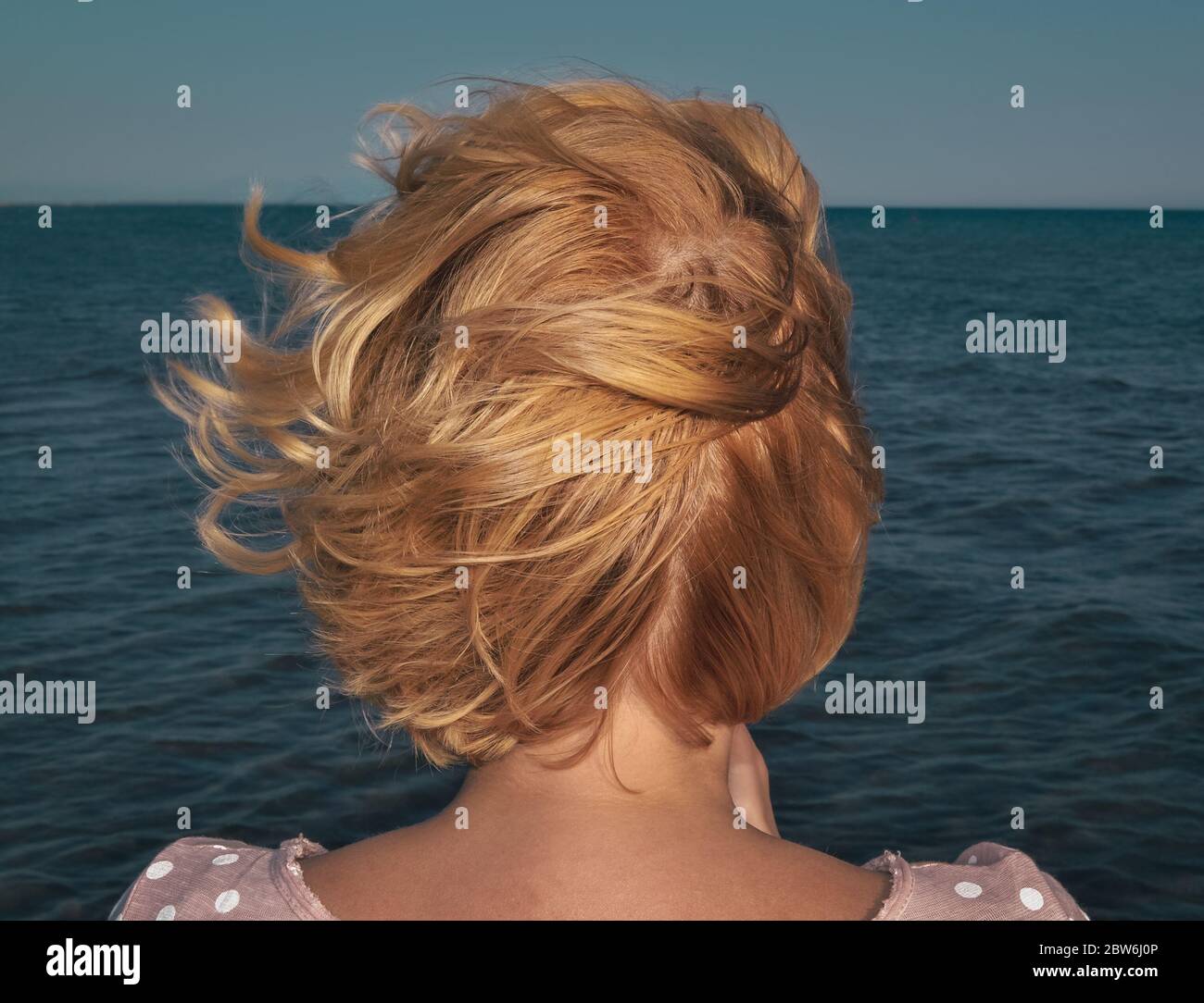 Femme avec de beaux cheveux blonds près de la mer regardant l'horizon Banque D'Images