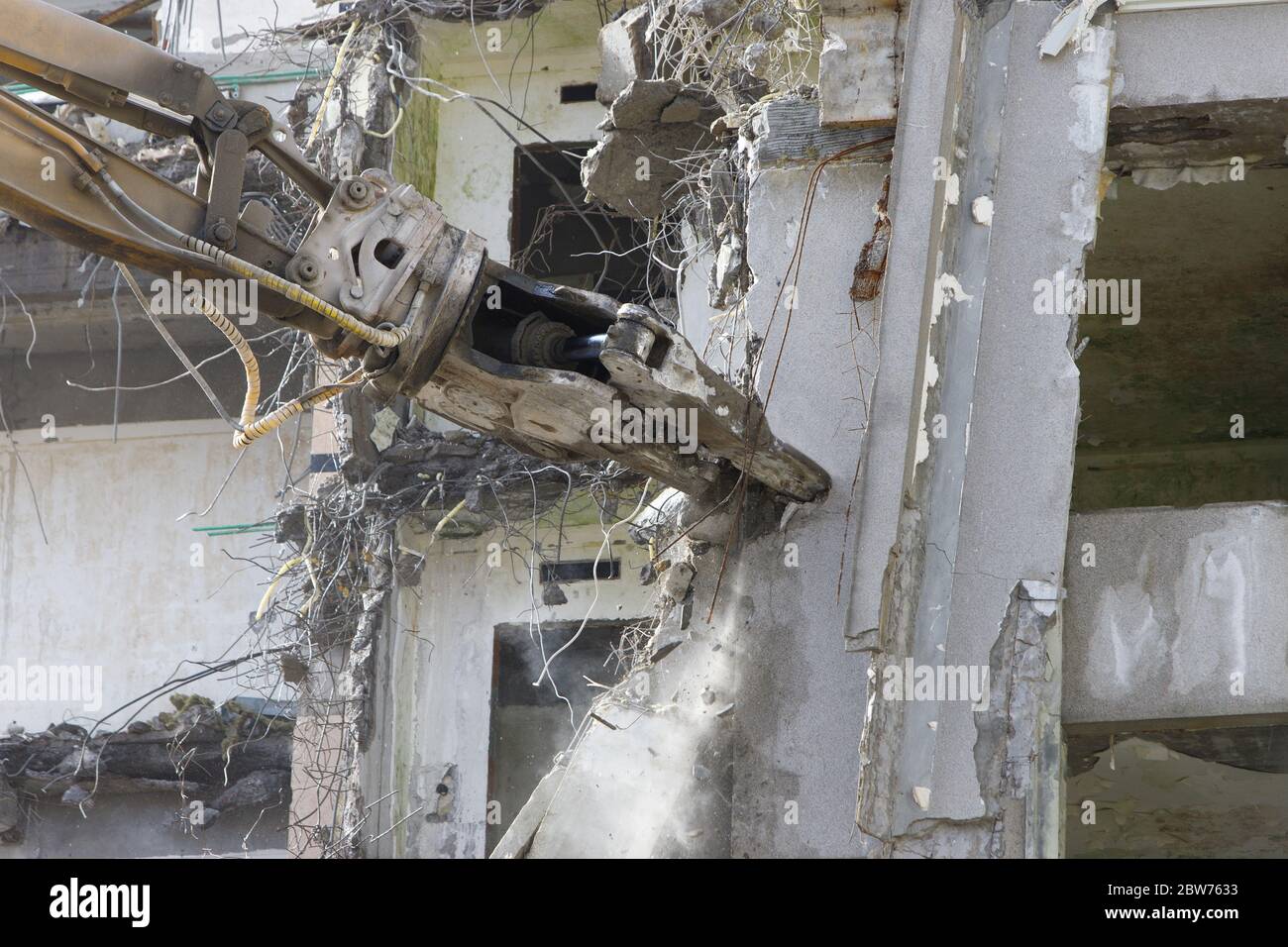 Démolition de bâtiments. Saisir la grue avec les ciseaux hydrauliques de fermeture. Structures en béton armé. Banque D'Images