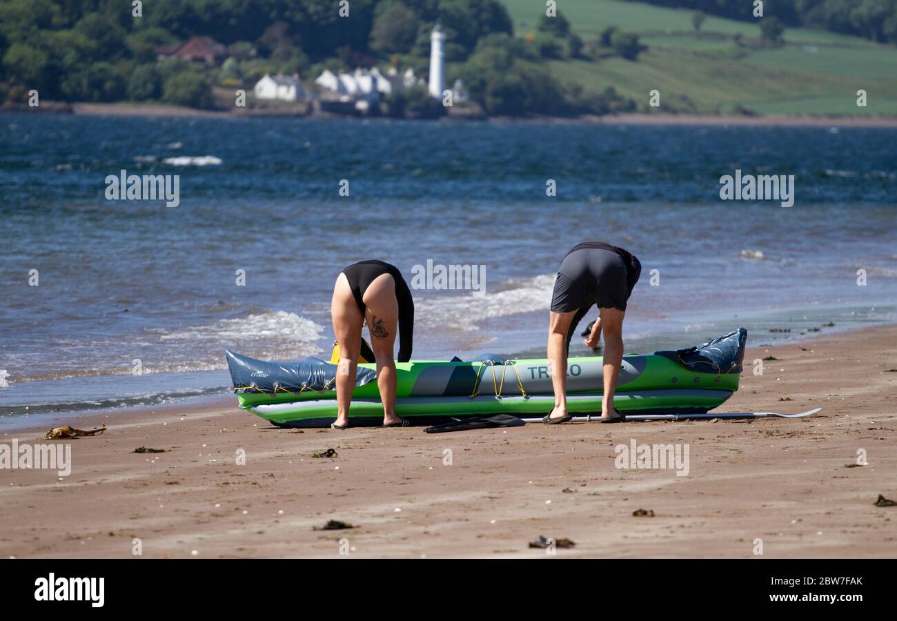 Dundee, Tayside, Écosse, Royaume-Uni. 30 mai 2020. Météo au Royaume-Uni : le temps chaud et ensoleillé continue de traverser le nord-est de l'Écosse, bien que relativement terne sur la côte. Aujourd’hui, c’est le troisième jour, phase 1 du plan en quatre étapes du gouvernement écossais pour sortir de son isolement, permettant aux gens de passer plus de temps à l’extérieur tout en suivant les directives de distanciation sociale. Un couple qui prend son kayak gonflable TR 3.0 sur l'estuaire de la rivière Tay le long de la plage de Broughty Ferry à Dundee. Crédit : Dundee Photographics/Alamy Live News Banque D'Images