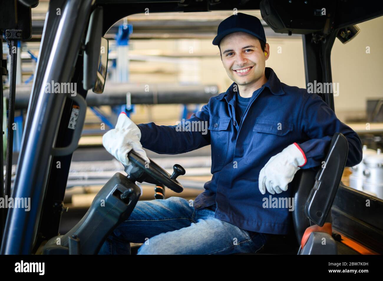 Un beau ouvrier de la construction conduisant un chariot élévateur dans une usine industrielle Banque D'Images