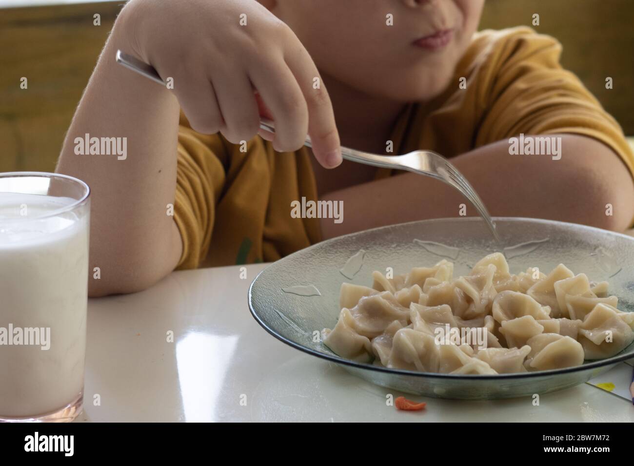 garçon enfant mangeant des pâtes dans la cuisine avec yaourt Banque D'Images