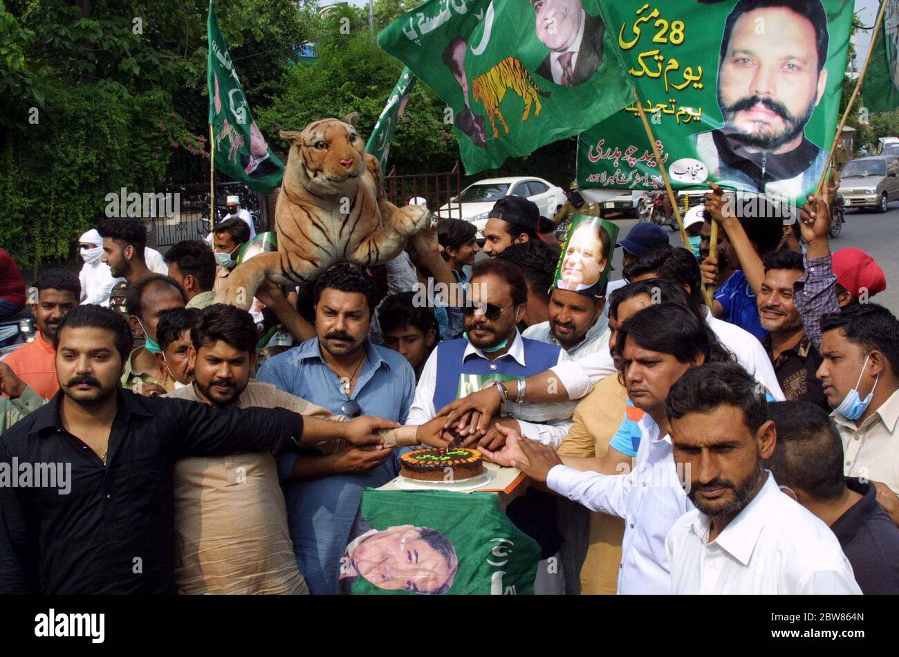 Les dirigeants et les activistes de la Ligue musulmane (PML-N) ont coupé le gâteau lors de la cérémonie de célébration à propos de Youm-e-Takbeer (le jour où le Pakistan a effectué des essais nucléaires le 28 mai 1998, en réponse aux explosions nucléaires indiennes), devant le club de presse de Lahore le samedi 30 mai 2020. Banque D'Images