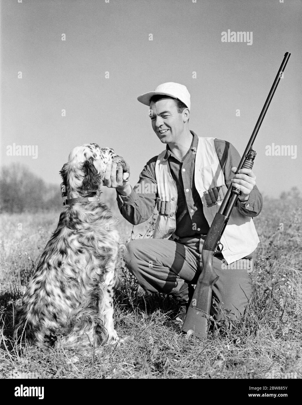 DANS LES ANNÉES 1960, HOMME SOURIANT CAILLE HUNTER AGENOUILLÉ AVEC POMPE À POMPE À FUSIL DE CHASSE PRENDRE L'OISEAU DE LA BOUCHE DE SON CHIEN DE RETRIEVER ANGLAIS - G5149 HAR001 HARS MÂLES HUNTER ANGLAIS B&W CHASSE À GENOUX COMPÉTENCE ACTIVITÉ AMUSEMENT BONHEUR MAMMIFÈRES AVENTURE SON HOBBY LOISIR CANINES HOBBIES SAVOIR PASSE-TEMPS DISPOSITIF DE RÉGLAGE AUTOMNE PLAISIR ANGLAIS SETTER CONNEXION RETRIEVER WILD JEU CANINE COOPÉRATION ARME À FEU CHASSEURS MAMMIFÈRES ADULTE MOYEN-ADULTE HOMME DÉTENTE TOGETHERNESS AMATEUR AUTUMNAL OISEAU CHIEN NOIR ET BLANC CAUCASIEN PLAISIR ETHNIQUE CHUTE FEUILLAGE HAR001 OLD FASHIONED Banque D'Images