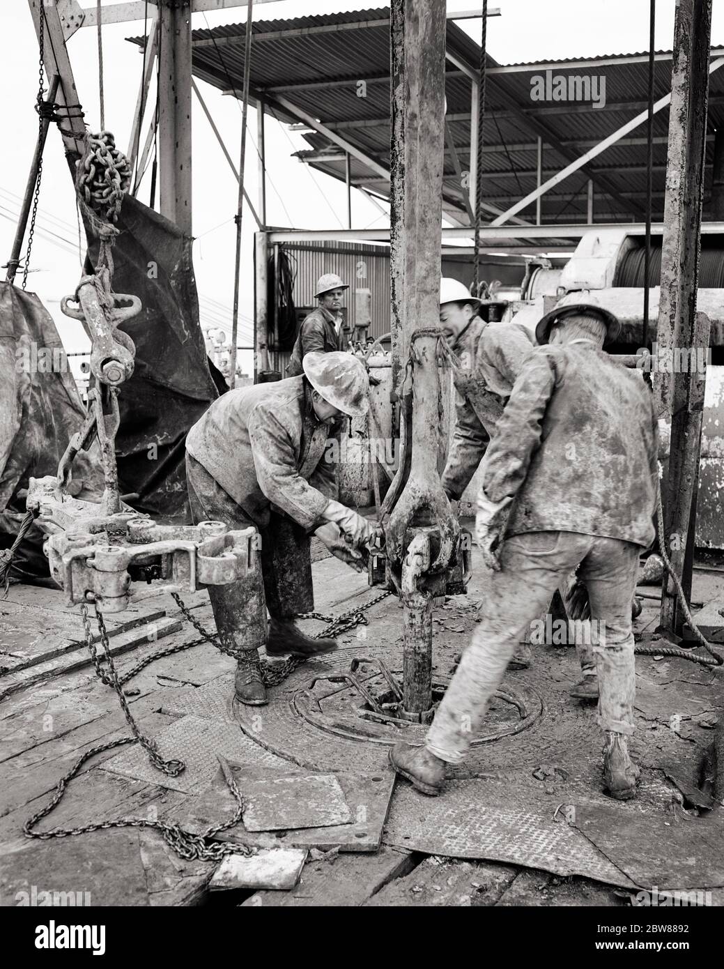 ANNÉES 1960 QUATRE HOMMES HROUGHNECKS FOREURS PORTANT DES CASQUES DE SÉCURITÉ ET DES VÊTEMENTS EN TOILE TRAVAILLANT SUR LE FORAGE PÉTROLIER OFFSHORE DANS LE GOLFE DU MEXIQUE - I3161 HAR001 HARS COMPÉTENCES GRAND ANGLE FORAGES DANGEREUX MANUEL FORCE CARRIÈRES EMPLOI DANGEREUX EMPLOIS DANGEREUX RISQUES RISQUES RISQUES OFFSHORE RISQUES CONCEPTUEL GOLFE DU MEXIQUE SOUTIEN EMPLOYÉ DANGER COOPÉRATION COMMERCIALE ADULTE MOYEN ADULTE HOMME MOYEN-ADULTE PÉTROLE JEUNE HOMME ADULTE NOIR ET BLANC RACE BLANCHE COMBUSTIBLE FOSSILE HAR001 LABOURING OLD FASHIONED Banque D'Images