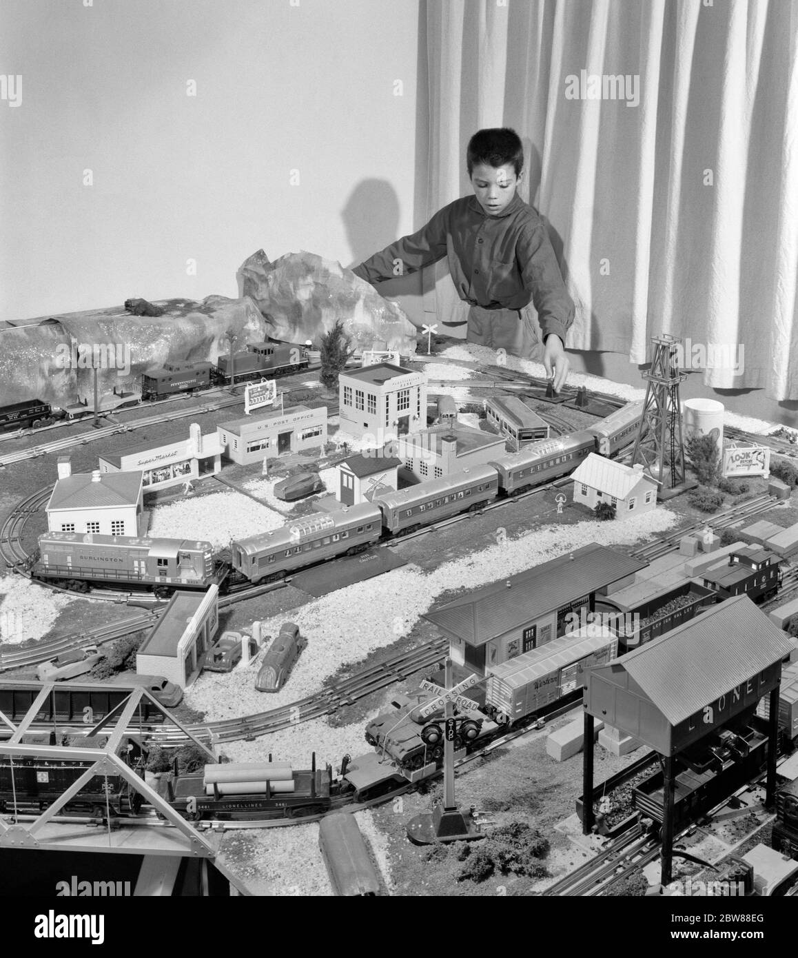 UN GARÇON DES ANNÉES 1950 JOUANT AVEC UN TRAIN MODÈLE ET UN VILLAGE JOUET SUR UNE GRANDE TABLE PASSE-TEMPS CHEMIN DE FER - J11021 HEL001 HARS HOMMES TRANSPORT B&W PRÉADOLESCENCE GARÇON RAIL COMPÉTENCE ACTIVITÉ AMUSEMENT RÊVES OCCUPATION GRAND ANGLE PASSE-TEMPS LOISIR LOISIRS SAVOIR LOISIRS PASSE-TEMPS PLAISIR PRÉADOLESCENCE CHEMINS DE FER JEUNES MODÉLISATION PRÉ-ADOLESCENT PRÉ-ADOLESCENCE DÉTENTE AMATEUR LE PLAISIR ETHNIQUE DU CAUCASE NOIR ET BLANC EST VIEUX Banque D'Images