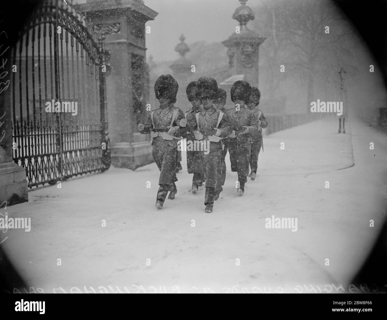 Temps réel de la région viticole à Londres . Une scène à l'extérieur de Buckingham Palace pendant le changement des gardes montrant des gardes marchant dans la neige à fourrure . 10 février 1932 Banque D'Images