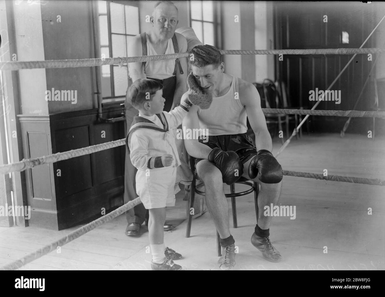 Le fils de Len Harvey visite le camp d'entraînement de son père pendant son entraînement pour le match du titre du monde . Terry sponsing le visage de son père après un sort de formation . 18 juin 1932 Banque D'Images