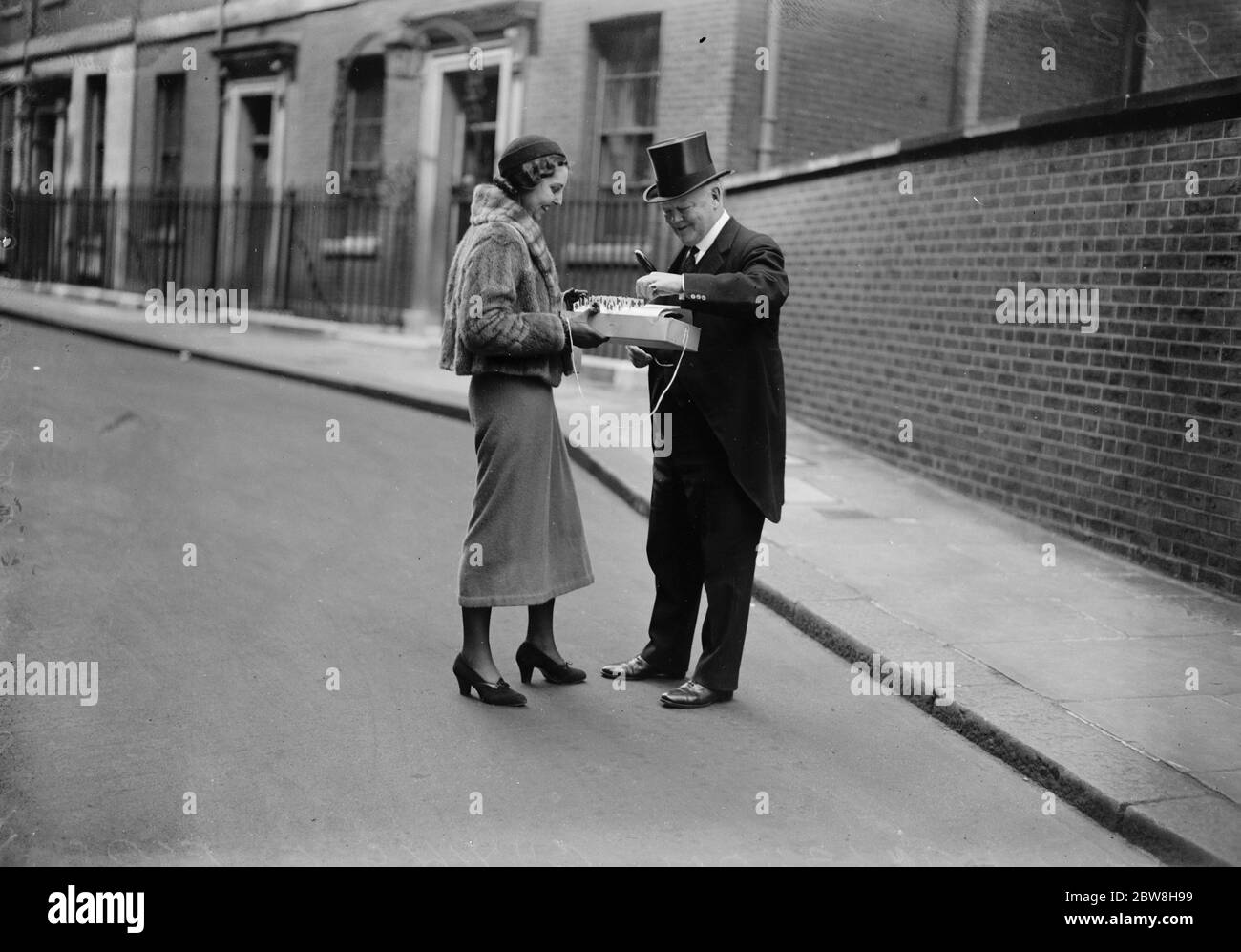 Le Secrétaire de guerre assiste à la réunion sur le désarmement . Lord Hailsham achète un drapeau vendu à l'aide des fonds de la Croix-Rouge , à son départ . 12 mai 1933 Banque D'Images