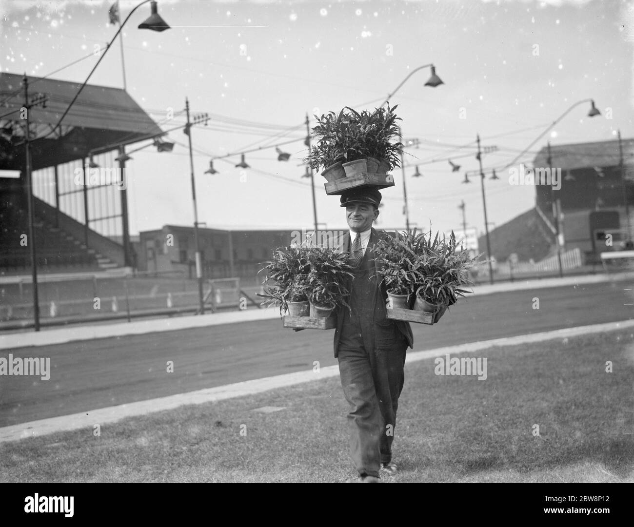 Un homme de terrain à Crayford Speedway Track fait bien de transporter des pots d'usine autour de la piste . 1936 Banque D'Images