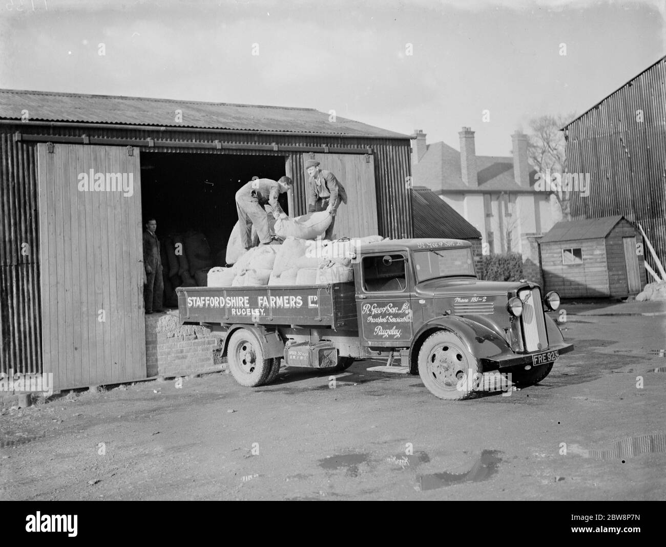Les travailleurs chargent des sacs à l'arrière d'un camion appartenant à R Gee and Sons , Rugeley ,Staffordshire . 1937 . Banque D'Images
