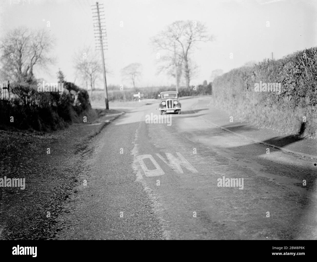 Conditions de route - un panneau de route usé partiellement couvert de nouveau tarmac , Stafford . 1937 . Banque D'Images