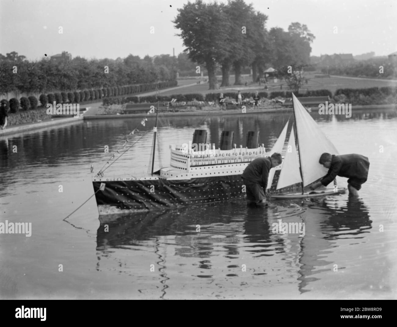 Modèle du paquebot RMS Queen Mary est libéré sur l'eau à côté d'un yacht modèle . 1936 Banque D'Images