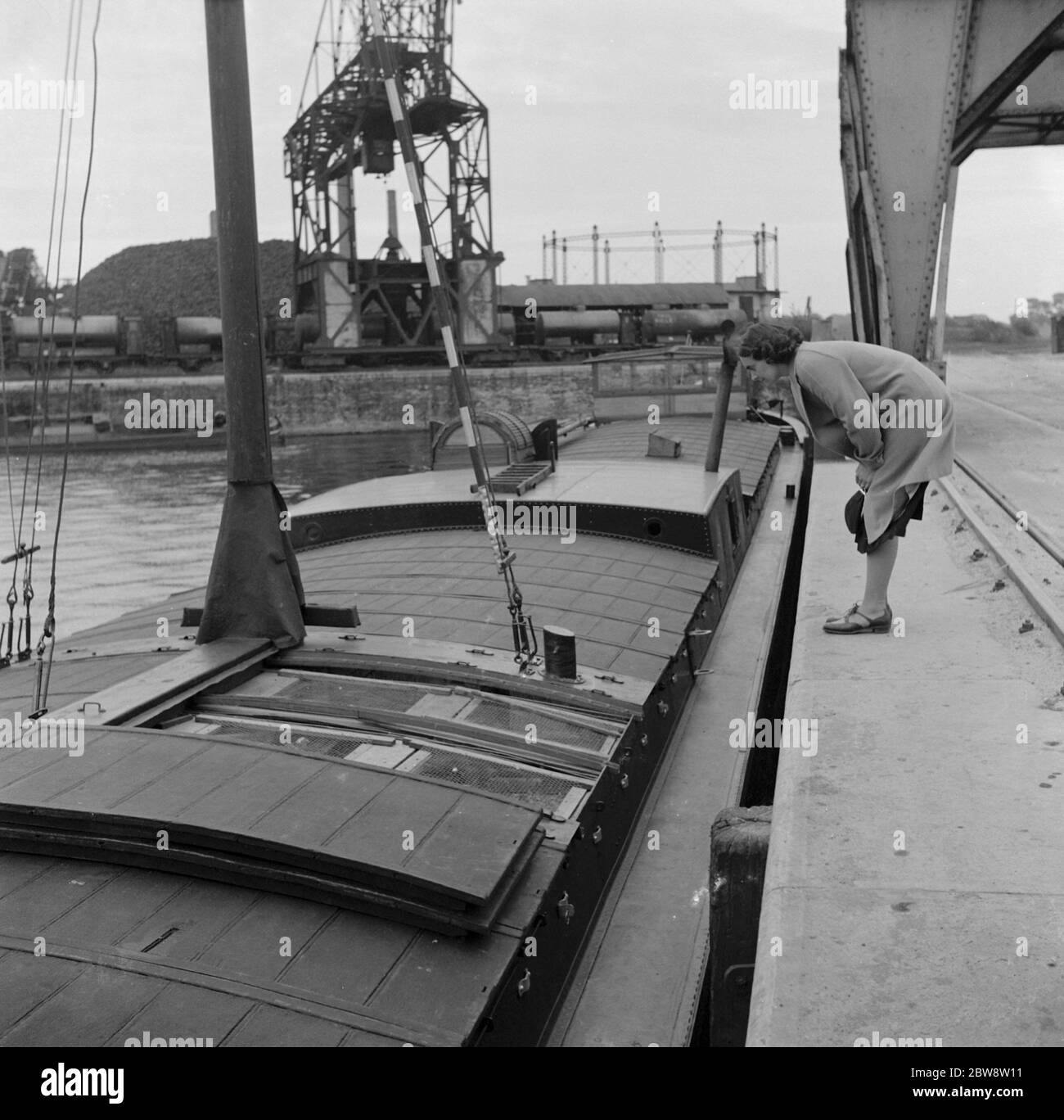 Une femme regarde dans une cage de pidgeon sur une barge hollandaise . 1938 Banque D'Images