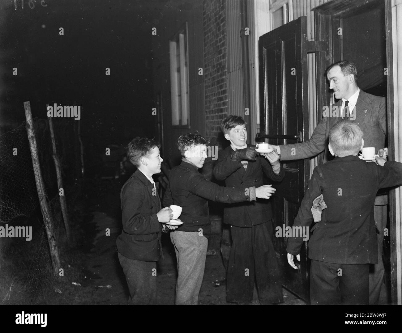 Les garçons reçoivent des tasses de thé à l'extérieur de la salle de fête . 1937 Banque D'Images
