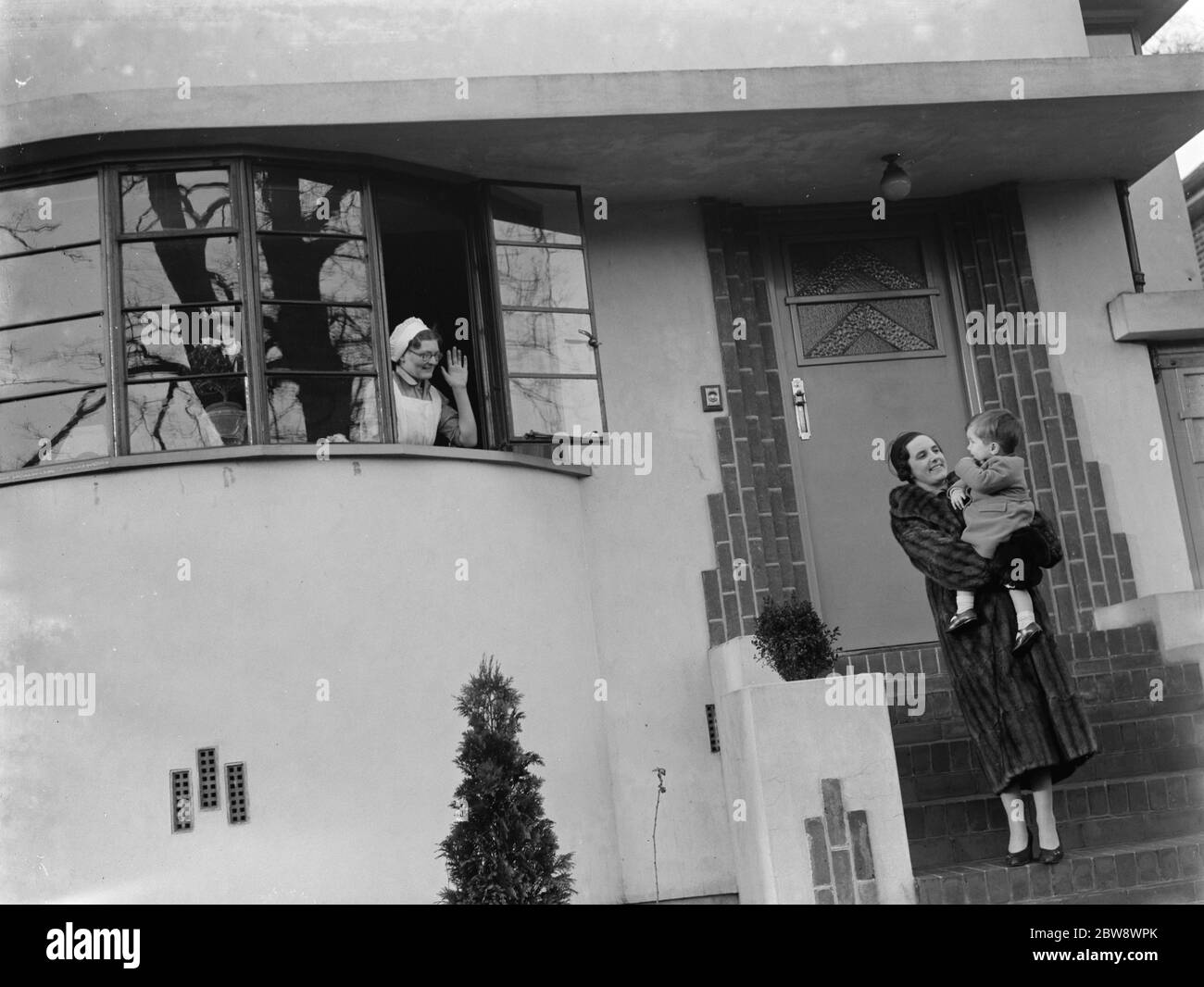 Mme Zehnder avec son petit garçon , sur les portes de sa maison . La nounou les fait au revoir de la fenêtre . Photos publicitaires prises pour le Daily Mirror . 1937 Banque D'Images