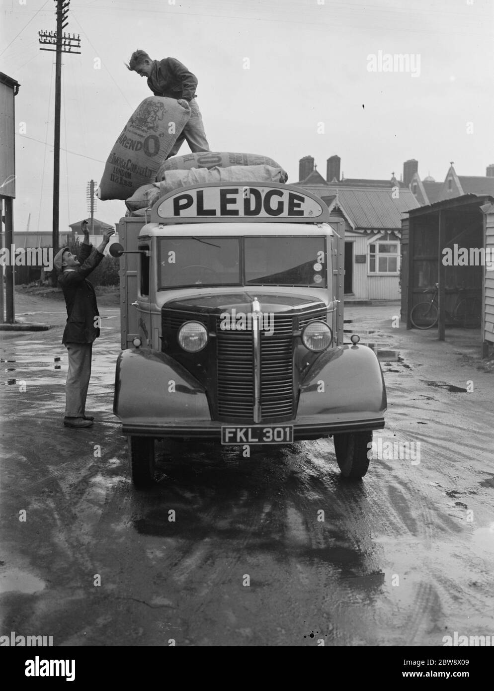 Les travailleurs déchargent des sacs d'un camion Bedford appartenant à la société de broyage de nantissement & son Ltd , lors d'une de leurs livraisons à Ashford , dans le Kent . 1939 Banque D'Images