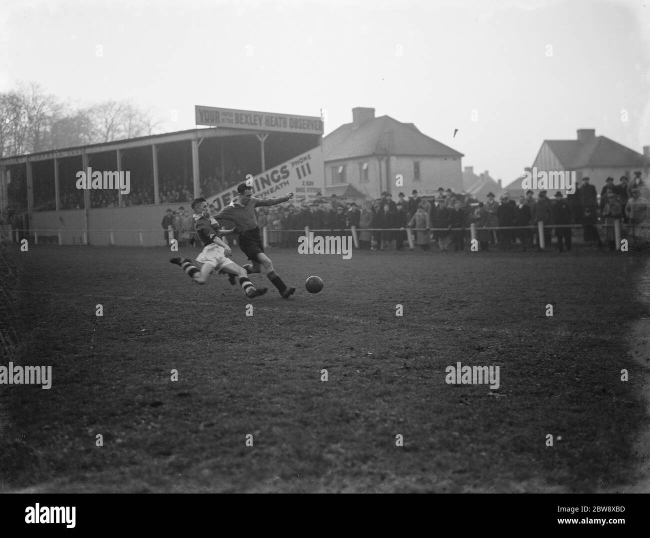 Bexleyheath et Winelling c. London Paper Mills - Kent League - 05/12/36 un attaquant se renverse sur un défenseur au bord de la boîte . 1936 Banque D'Images