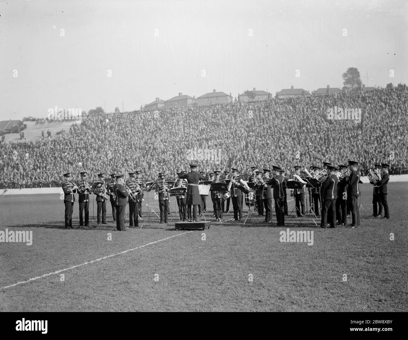 Un groupe joue à un stade emballé pendant un match de football . 1938 Banque D'Images