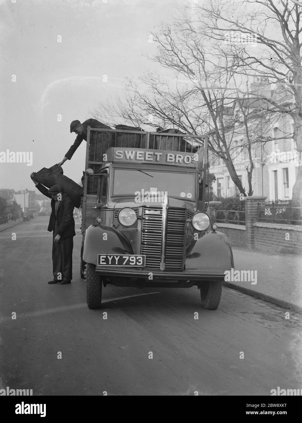Les travailleurs déchargent les sacs d'un camion de Bedford appartenant à Sweet Bros, le marchand de charbon , à leur livraison . 1939 Banque D'Images