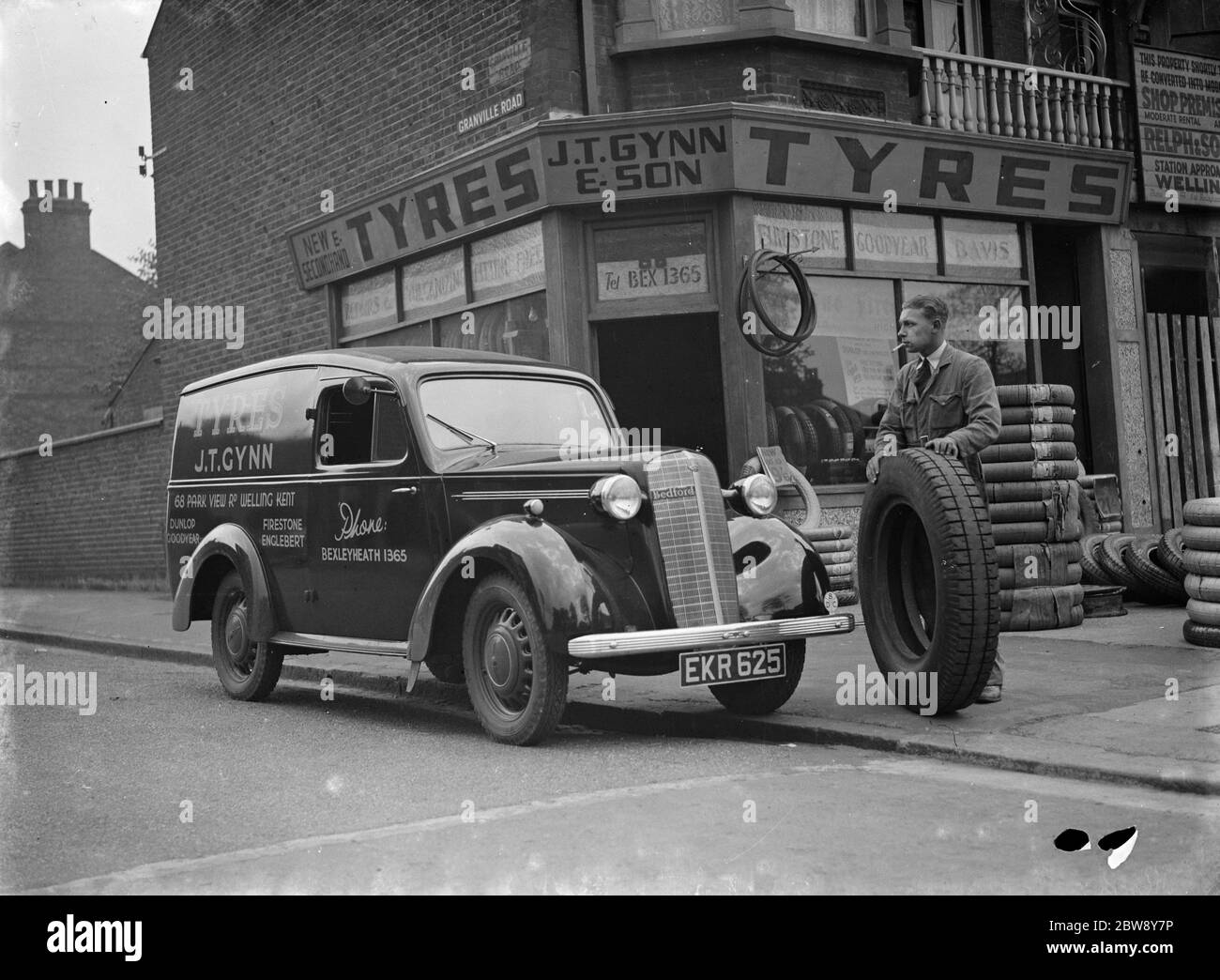 Un magasin J T Gynn et son Tires avec leur camion Bedford stationné à l'extérieur , à Bexleyheath , dans le Kent . Un homme charge la camionnette avec des pneus . 1938 Banque D'Images