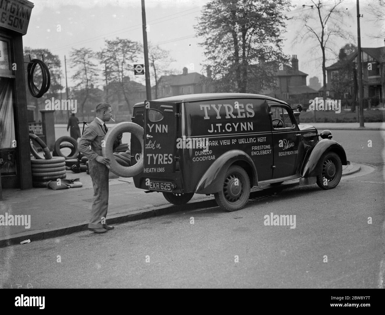 Un magasin J T Gynn et son Tires avec leur camion Bedford stationné à l'extérieur , à Bexleyheath , dans le Kent . L'homme charge la camionnette avec un pneu . 1938 Banque D'Images