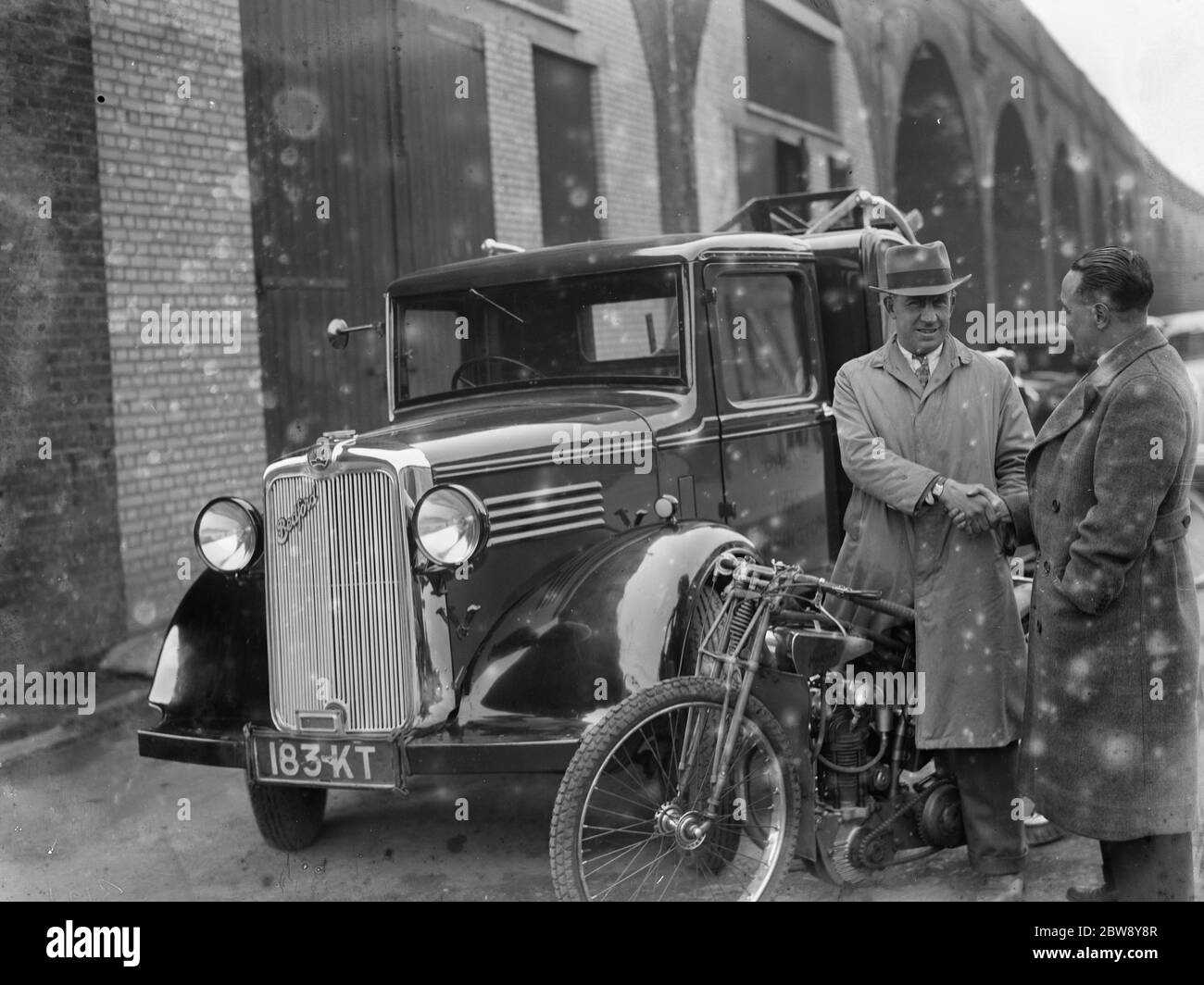Un homme à cheval sur un vélo de course à côté d'un treuil Bedford, à proximité du New Cross Stadium à Londres. 1936 Banque D'Images