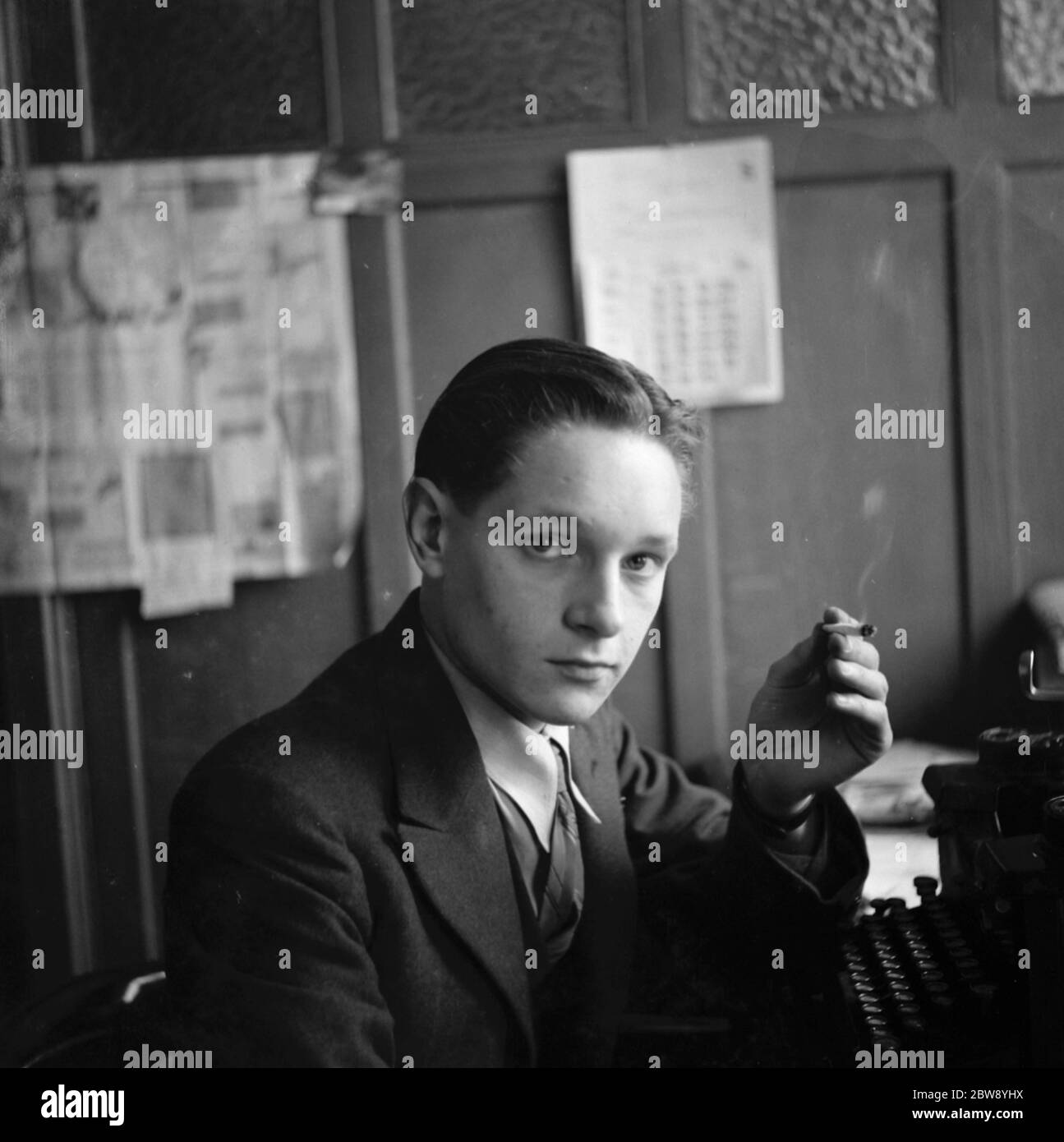 M. Gordon Grimley fume une cigarette à sa machine à écrire . 1939 Banque D'Images
