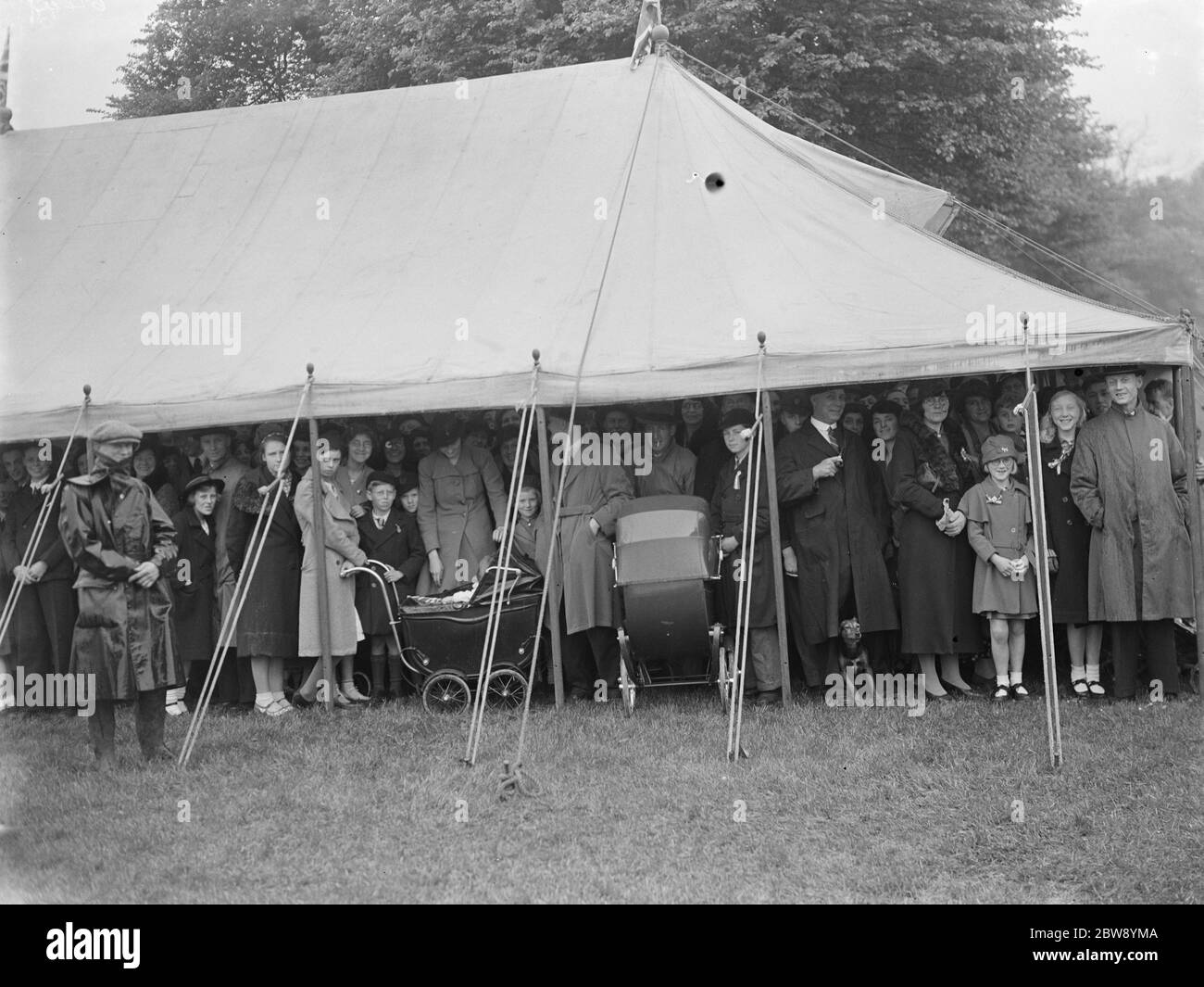 Festivités du couronnement à Bexleyheath , Kent , pour célébrer le couronnement du roi George VI . Les foules trouvent refuge contre la pluie sous un chapiteau . 15 mai 1937 Banque D'Images