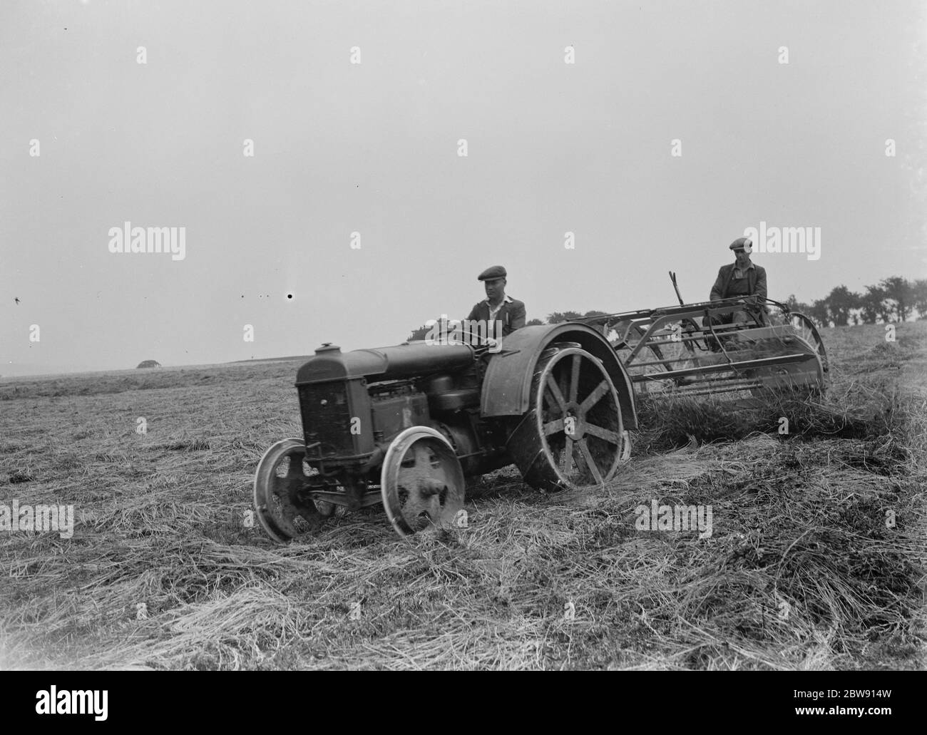 Les agriculteurs utilisant un nouveau tracteur tracent une machine de fabrication de foin sur un champ à Farningham , Kent . 16 juin 1937 Banque D'Images