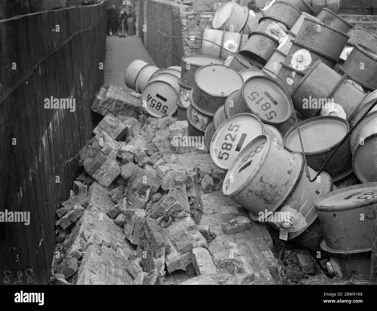 Un mur effondré près de la rivière à Greenwich montrant les débris dangereux ; tambours à huile et briques . 1938 Banque D'Images