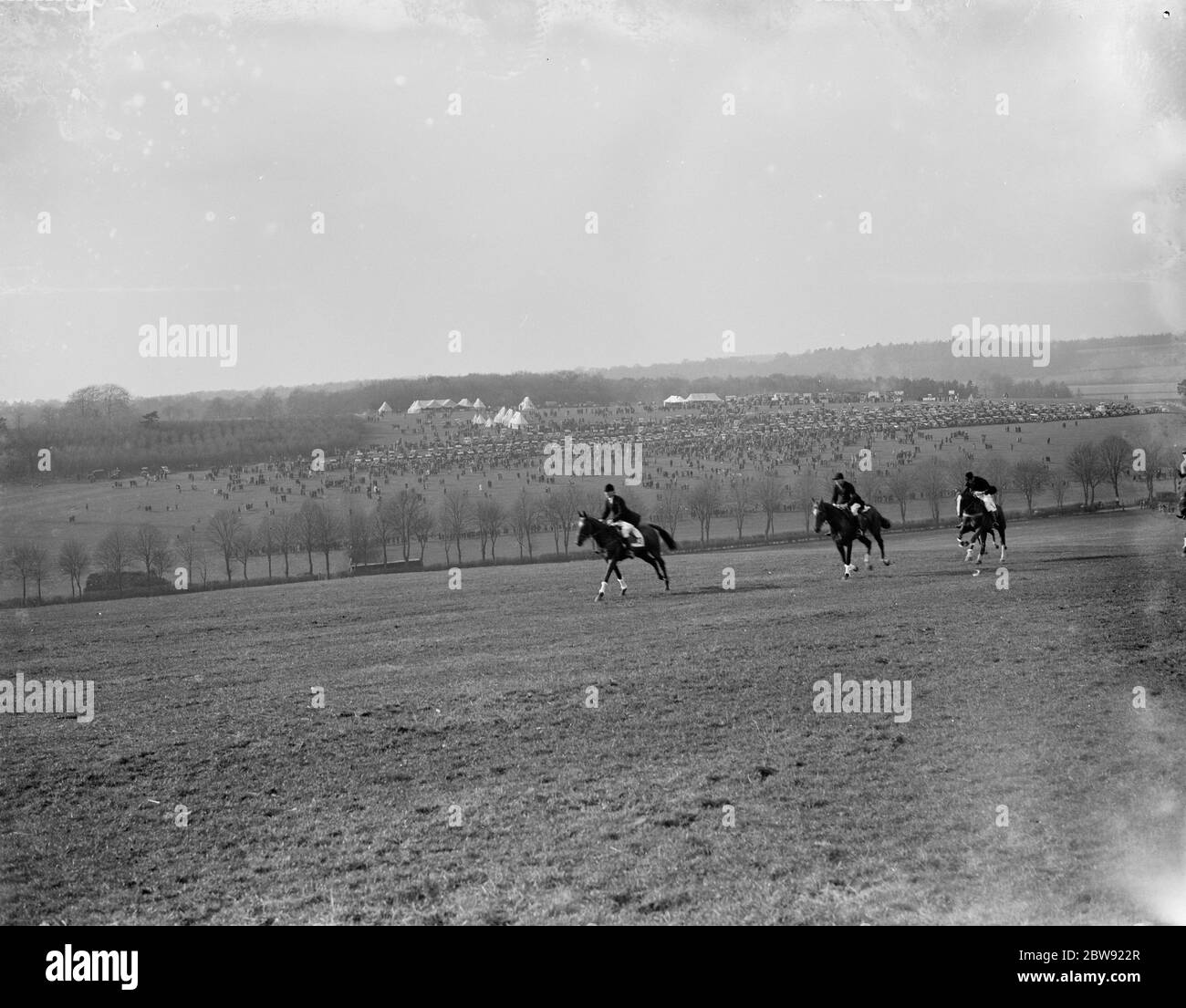 Les cavaliers se cantissent à travers le champ avec la vue de R A Woolwich point à point dans la distance . 1936 Banque D'Images