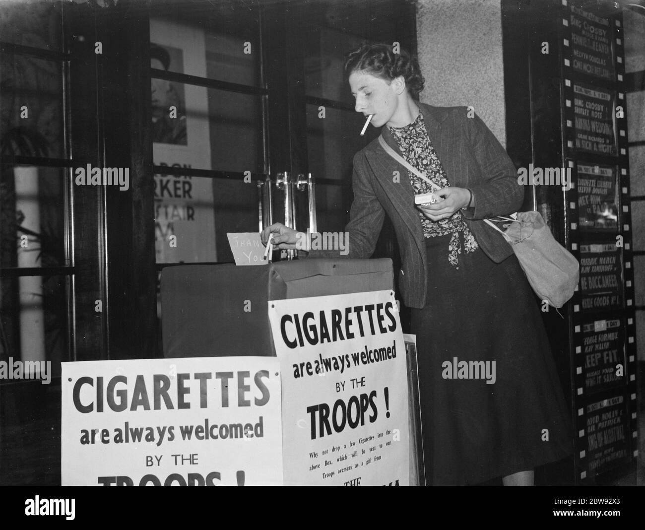 Mlle Nellie Simmonds jette quelques cigarettes dans une boîte de collecte pour les troupes. 1939 Banque D'Images
