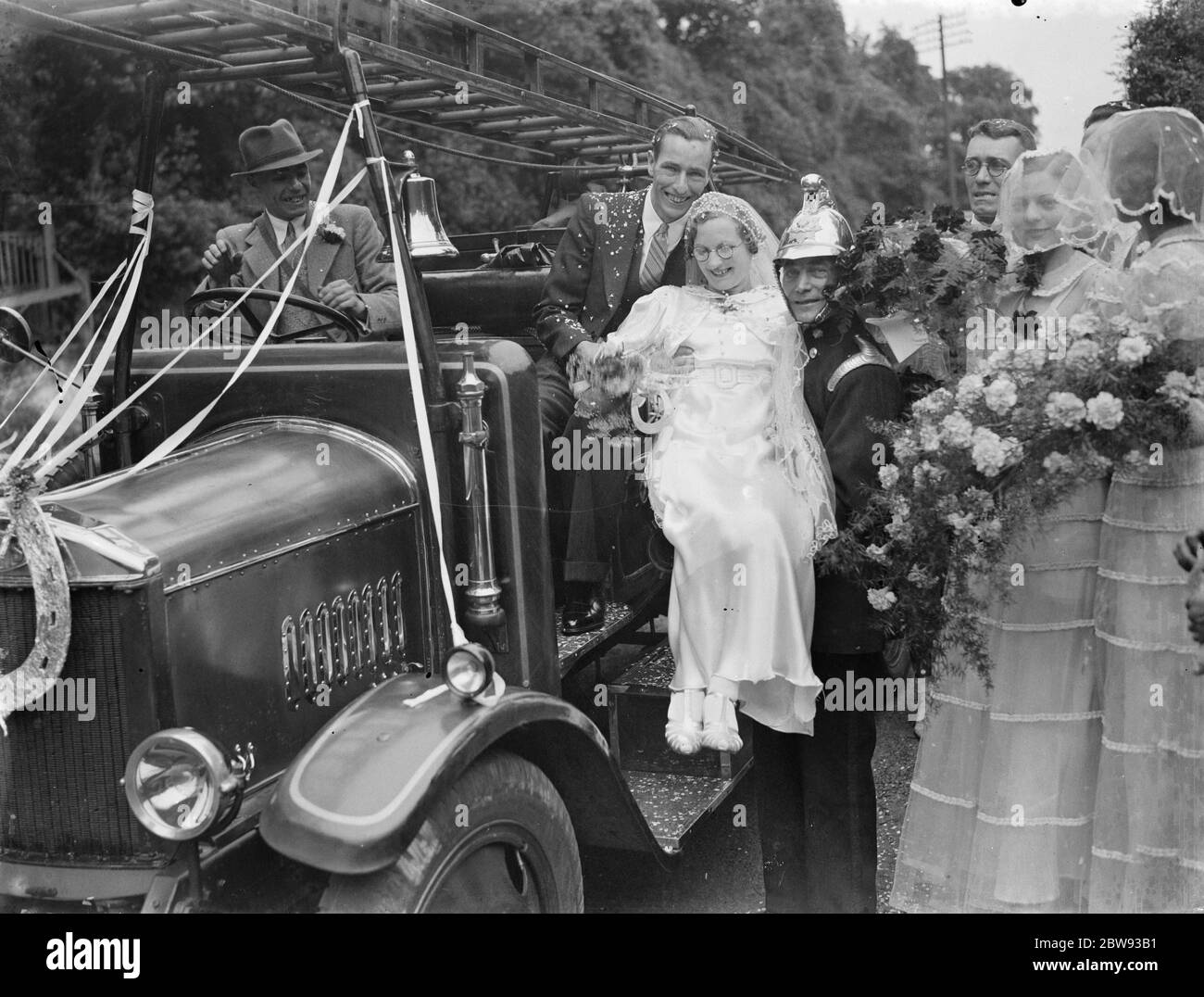 Le mariage de M. L Garland et de Mlle C Magee , le pompier. La mariée et le marié avec le moteur d'incendie . Pompier donne de l'aide à la mariée . 1939 Banque D'Images