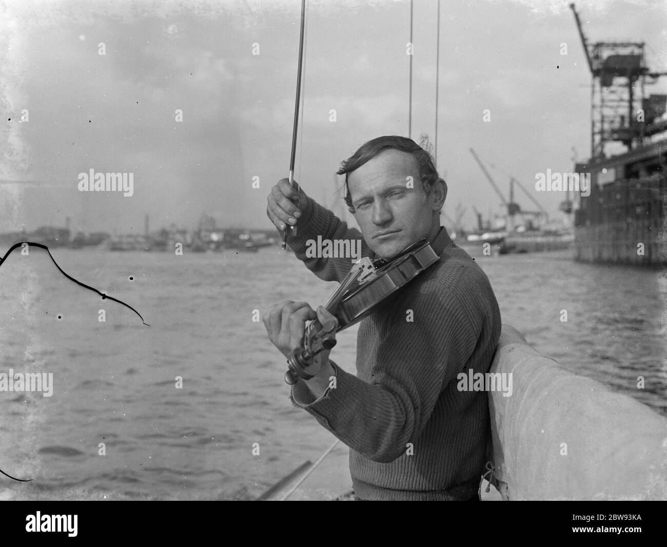Un peintre letton est de naviguer vers l'Amérique . Ici, il joue le violon du front du voilier avec lequel il va tenter l'exploit . 1939 Banque D'Images