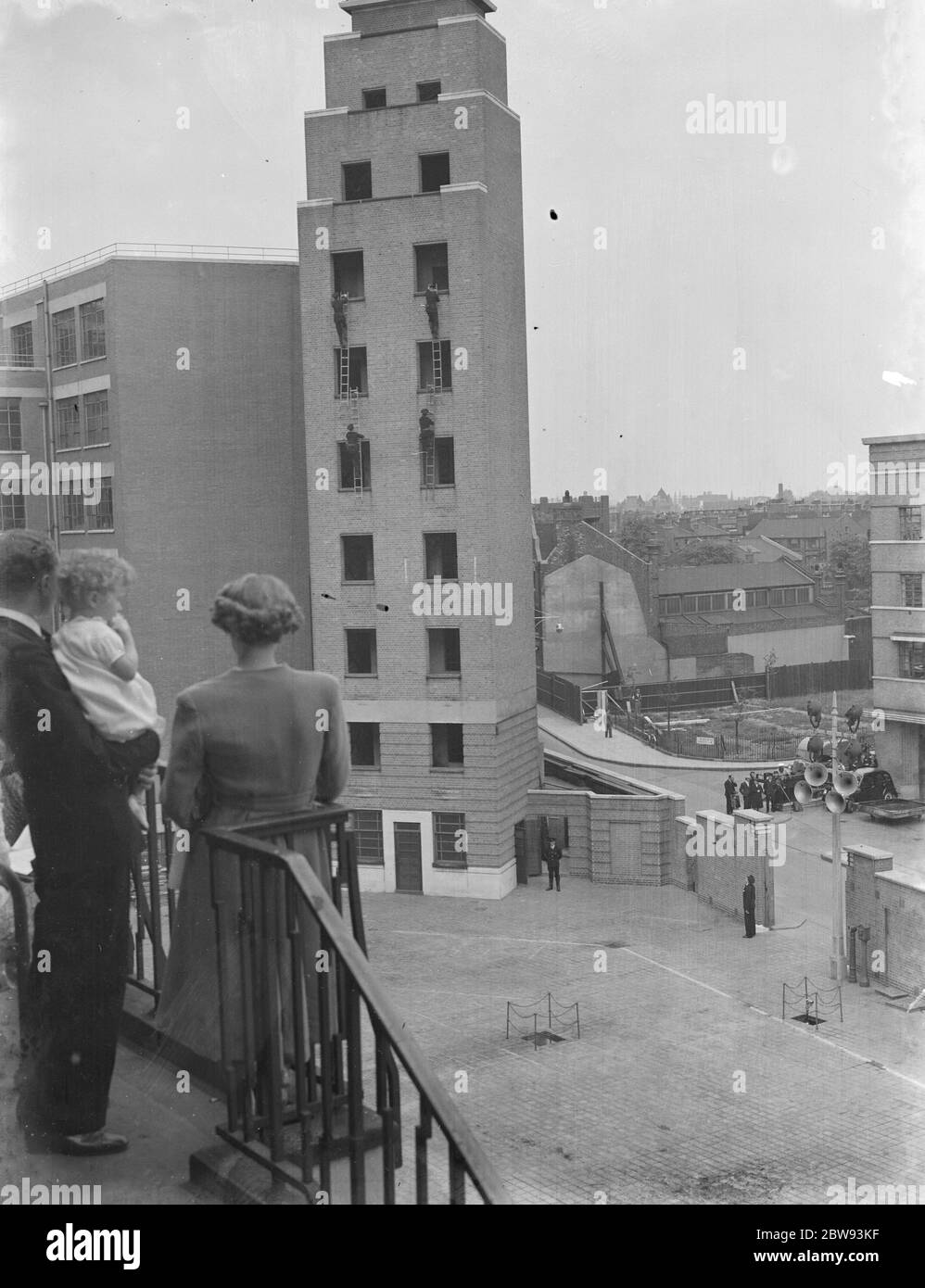 Un exposition de la brigade de pompiers de Londres à Lambeth , Londres. Les pompiers utilisent des échelles à crochets pour monter le grand bâtiment pendant la démonstration . 1939 Banque D'Images