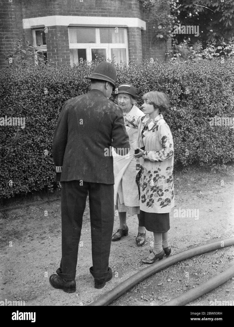 Des pompiers répondent à un incendie à Chislehurst , Kent . Un policier parle à Mme Evelyn Simpson . 1939 Banque D'Images