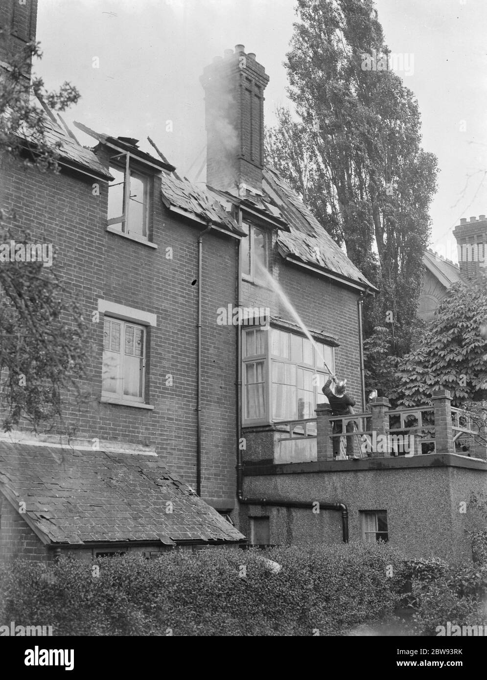 Des pompiers répondent à un incendie à Chislehurst , Kent . Un pompier tuyau de l'eau dans la fenêtre supérieure du bâtiment. 1939 Banque D'Images