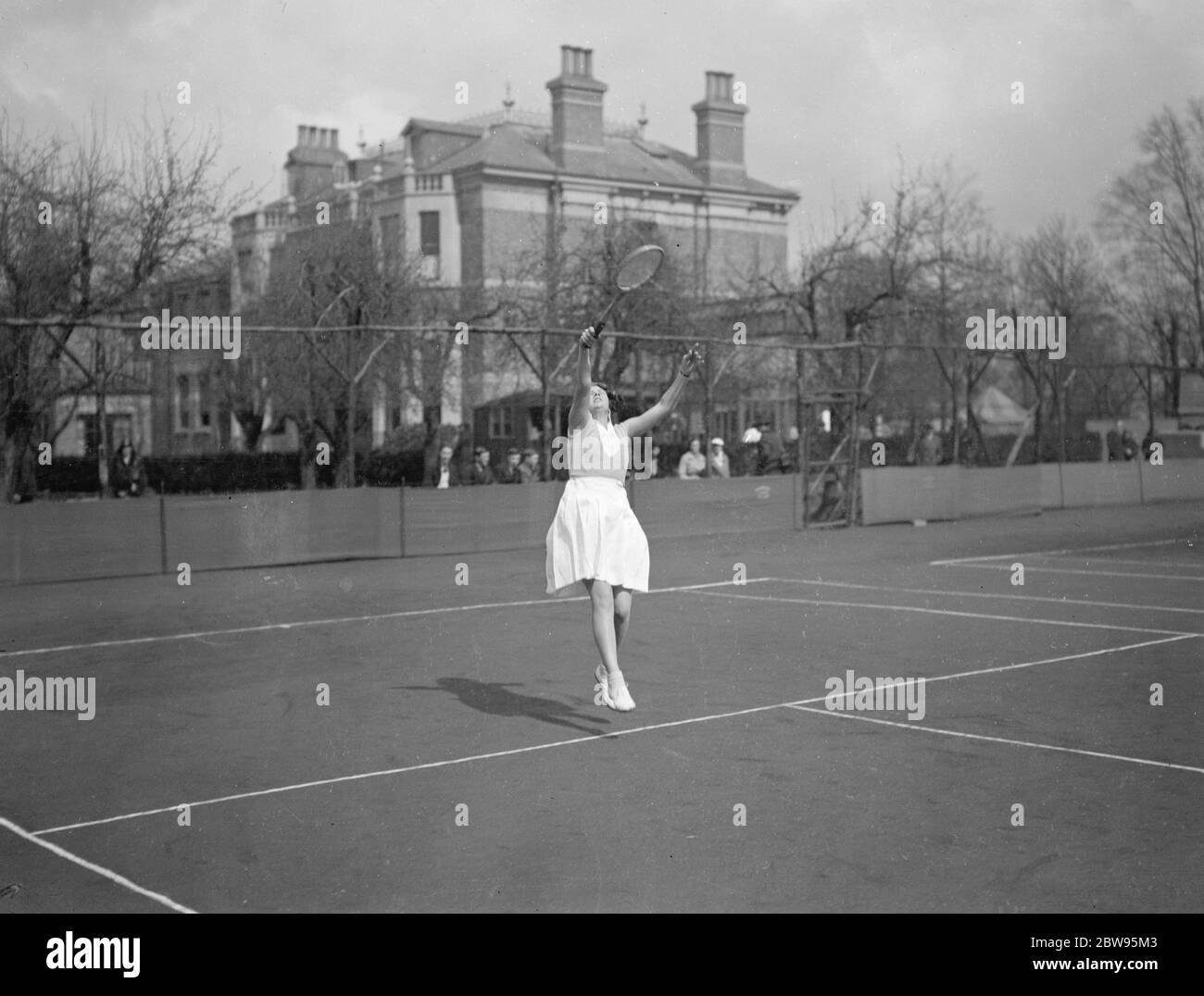 Tennis dans le vent au tournoi de tennis West Side à Ealing . Mlle R Jarvis en jeu dans le vent contre Mlle Smith , dans les singles féminins du West Side Country Club , Tournoi , à Ealing , Londres . 18 avril 1932 Banque D'Images
