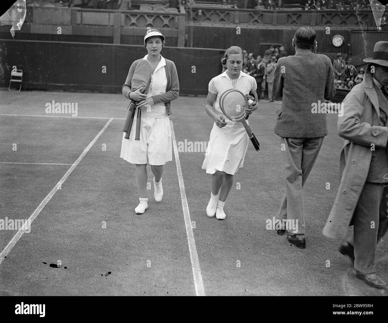 Helen Wills Moody bat Mary Heeley en demi-finale de Wimbledon . Mme Helen Wills Moody la star américaine de tennis a battu Miss Mary Heeley la jeune Birmingham , Angleterre , fille dans la demi-finale des femmes célibataires dans les championnats de tennis de Wimbledon . Score était 6-2 , 6-0 . Mme Wills Moody et Mlle Mary Heeley qui sont en train de sortir du terrain après le match . 30 juin 1932 Banque D'Images