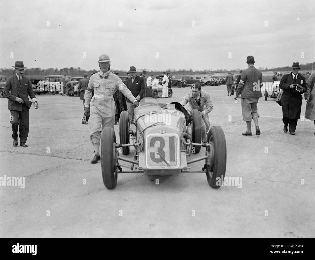 Course pour le trophée Empire britannique à Brooklands . De nombreux pilotes britanniques célèbres se sont alignés au début du club de pilotes de course britannique , Empire Trophy Race , à Brooklands Track , Weybridge , Surrey . La voiture conduite par Earl Howe poussant son entrée à la ligne de départ . 30 avril 1932 Banque D'Images