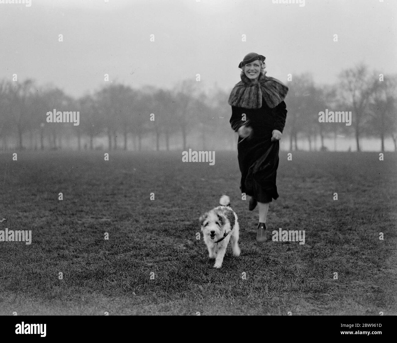 Comment garder en forme une poule dans le parc avec le chien est la méthode de Miss Heather Thatcher . Mlle Heather Thatcher , l' actrice , constate que le moyen le plus efficace de garder la forme est de faire une course quotidienne dans le parc avec son chien de compagnie Peter . Peter aime l'air frais autant que Miss Thatcher et il a appris un certain nombre de jeux . Il montre une grande intelligence pendant la pièce . Peter saute à un signal de sa maîtresse Miss Heather Thatcher , pendant une course à Hyde Park , Londres . 10 février 1933 Banque D'Images