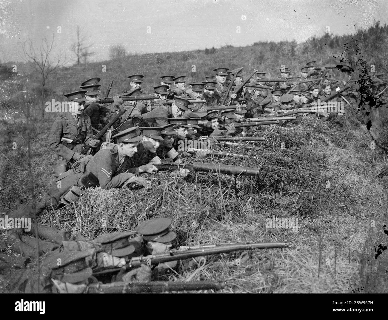 Les cadets de l'école de Harrow tiennent un jour de campagne à Aldershot . Le corps de formation des officiers de l'école de Harrow a eu la journée de campagne annuelle , réalisant des opérations dans la vallée de long à Aldershots . Les cadets de la herse tiennent position avec des fusils à la position prête dans un trou de feu . 1er mars 1932 Banque D'Images