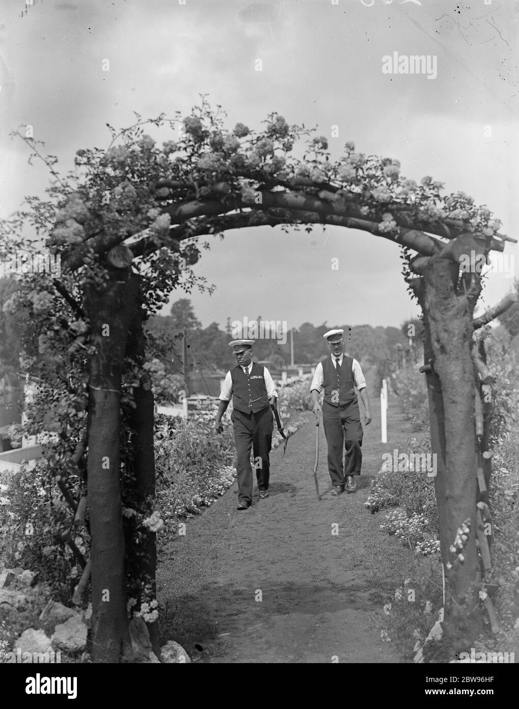 Le gardien de serrure de Teddington remporte la coupe de défi Sir Reginald Hanson pour les jardins de serrures les mieux gardés pour la troisième fois . Pour la troisième fois , M. A E Allen , gardien de l'écluse de Teddington , sur la Tamise, a reçu la coupe Sir Reginald Hanson Challenge pour les jardins les mieux gardés de l'écluse le long de la tamise . M. A E Allen ( à gauche ) marchant dans les jardins avec un de ses assistants . 27 juillet 1932 Banque D'Images