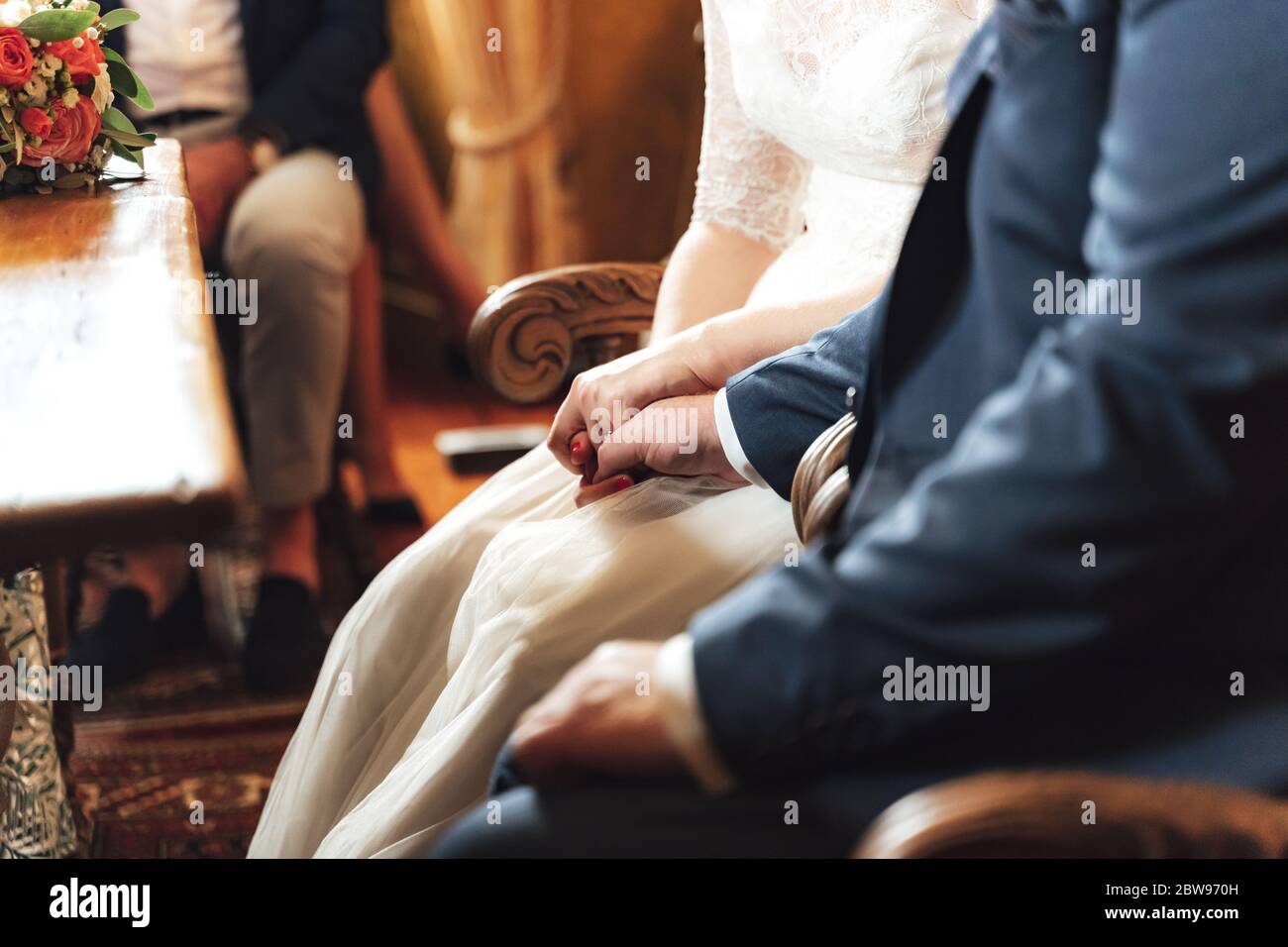 Couple de mariage assis sur des chaises pendant la cérémonie de mariage. Vue latérale gros plan des mains de l'homme et de la femme clastés. Couple aimant. Concept de mariage. Banque D'Images