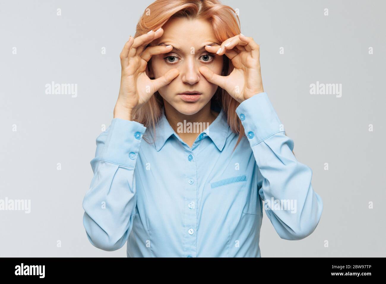 Très fatiguée jeune femme en chemise bleue veut dormir au travail ou à l'université, en ouvrant les yeux avec les doigts, en se calmant pour ne pas s'endormir. Manque Banque D'Images