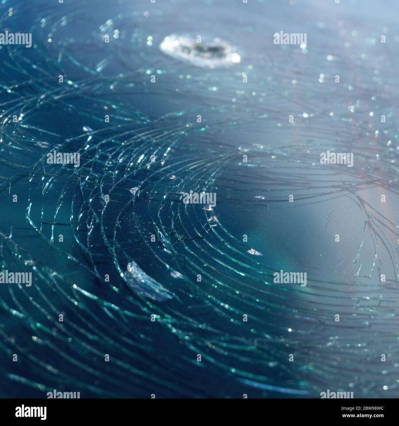 arrière-plan de voiture bleue pare-brise cassé recouvert de cercles de fissures. Trou sur le pare-brise. Banque D'Images