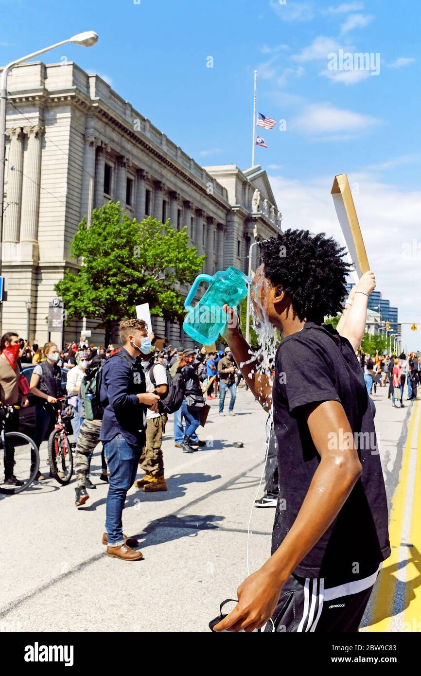 Un homme noir tente d'apaiser la douleur causée par les gaz lacrymogènes lancés par la police à Cleveland, Ohio, États-Unis, lors d'une manifestation contre la brutalité et le racisme de la police. La mort de George Floyd aux mains de la police à Minneapolis a suscité des manifestations dans des villes des États-Unis. Banque D'Images